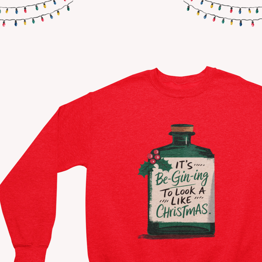 Close-up of the 'It's Be-Gin-Ning to Look a Lot Like Christmas' text on a cozy crewneck sweatshirt.